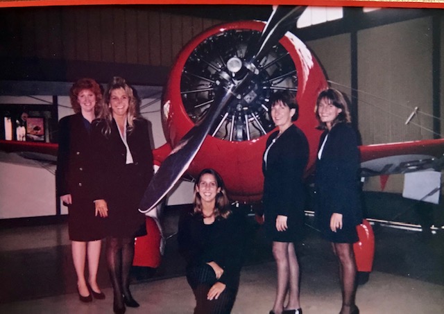 5 people standing in front of a single engine plane in the 90s