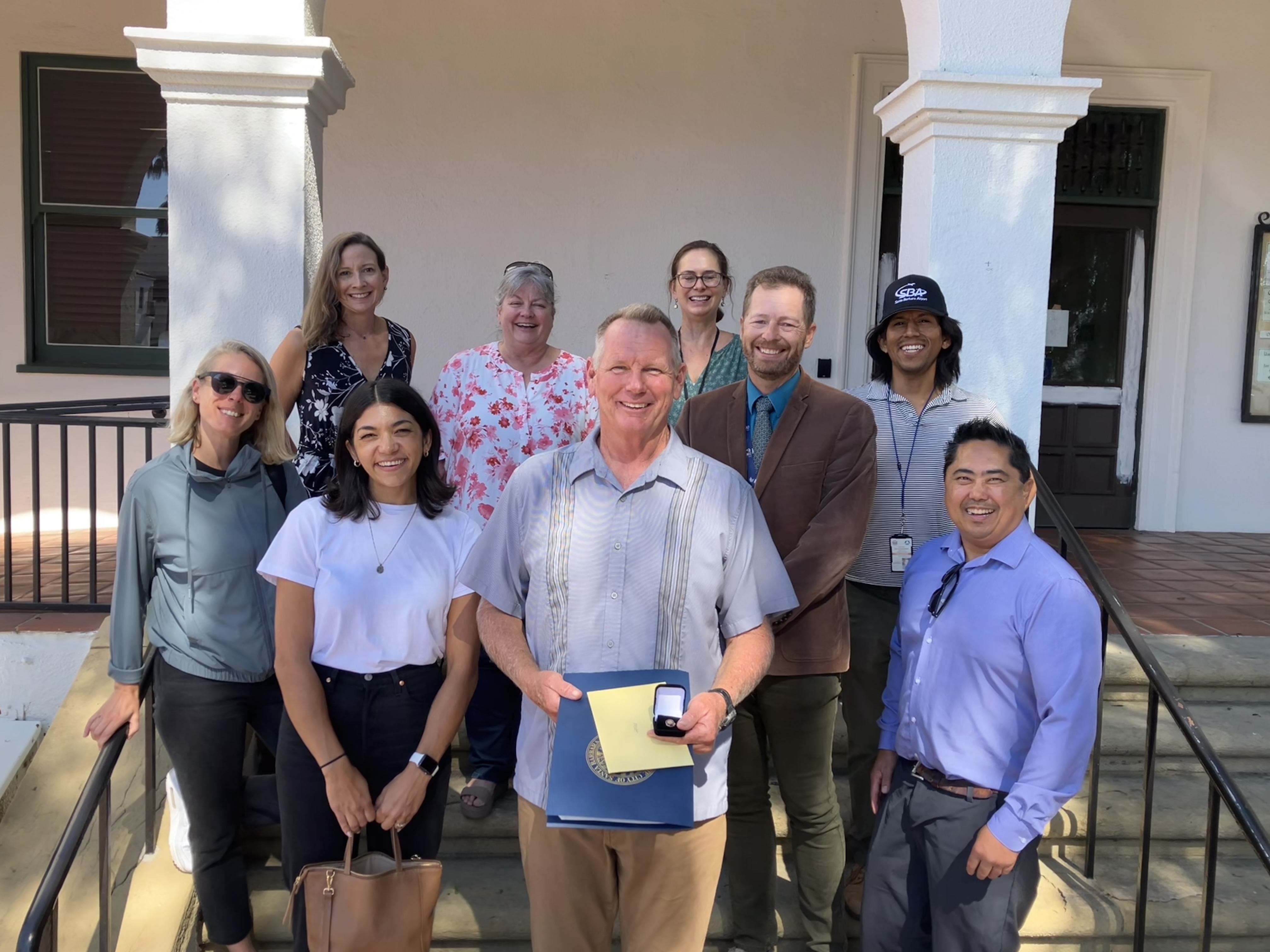 Matt Donahue poses with a group of employees holding a pin.