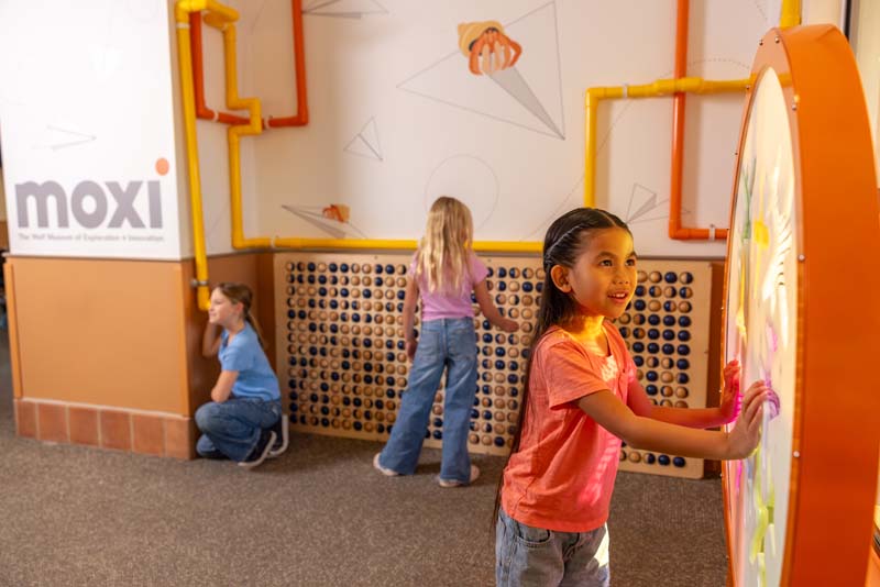 Three kids interact with the MOXI exhibit at SBA