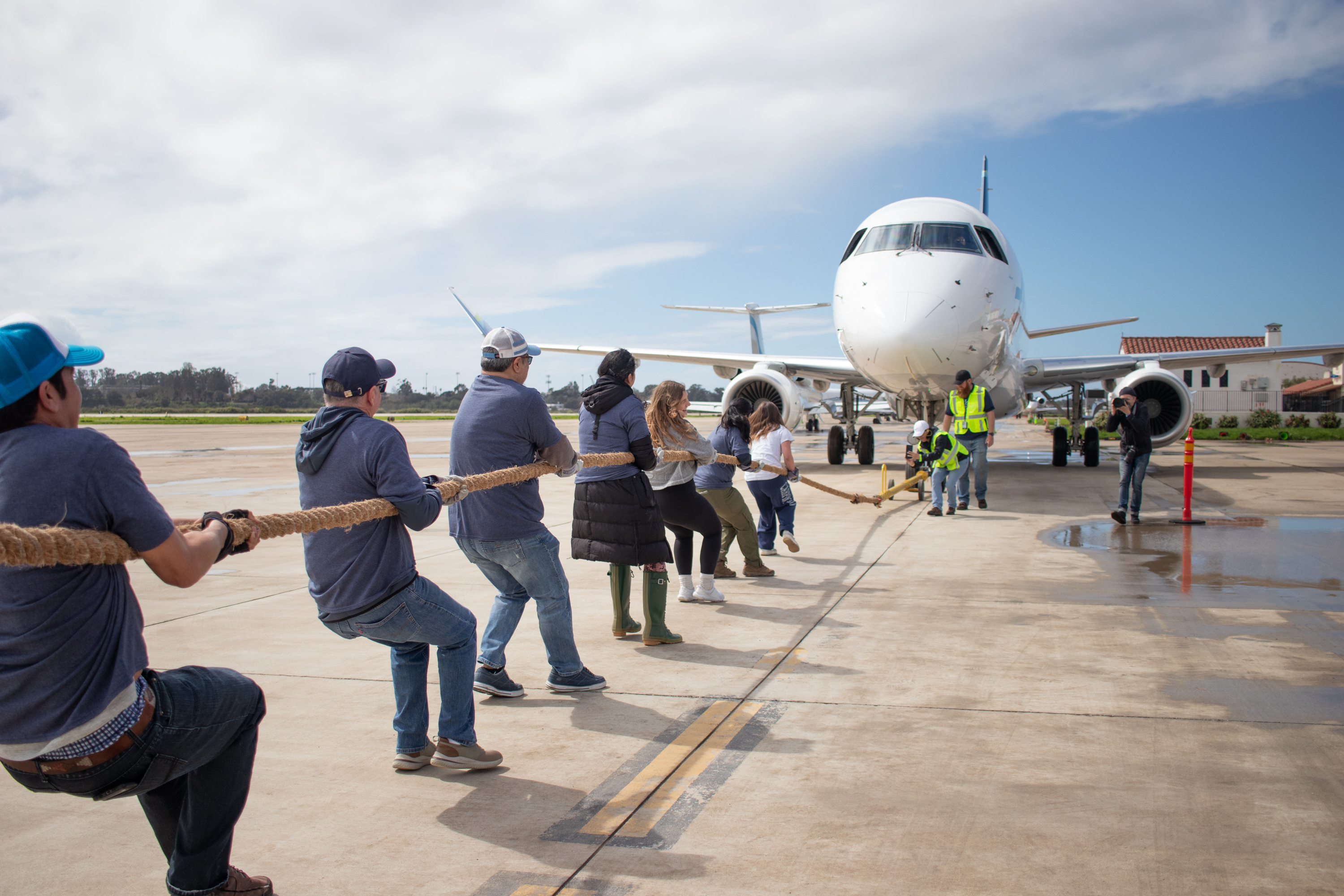 A group of people pull an airplane by a rope.