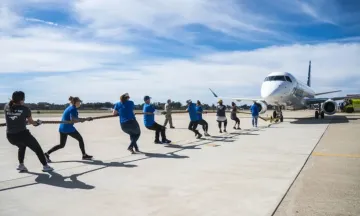 Team of 10 people pulling an airplane with a rope