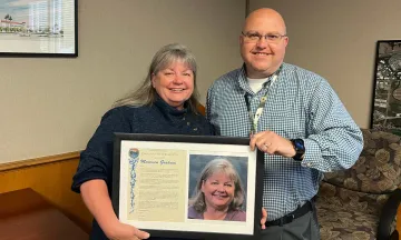 Mo Graham poses with Airport Director Chris Hastert holding a plaque