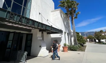 Two people walking into the main entrance of the Santa Barbara Airport Terminal 