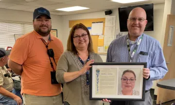 Julia poses with two airport staff and her Employee of the Month plaque