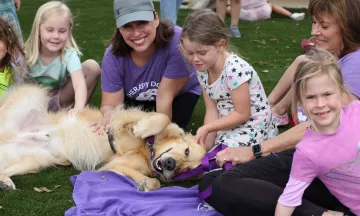 Therapy dog laying in grass with kids