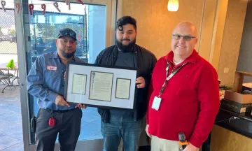 Two members of the custodial team pose with their plaque. 