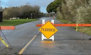 Road with a barricades and a sign that says "flooded"