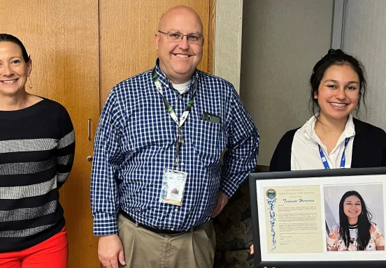 Teanna Herrera holding her recognition plaque, standing next to Chris (Airport Director) and Sara (Development Manager)