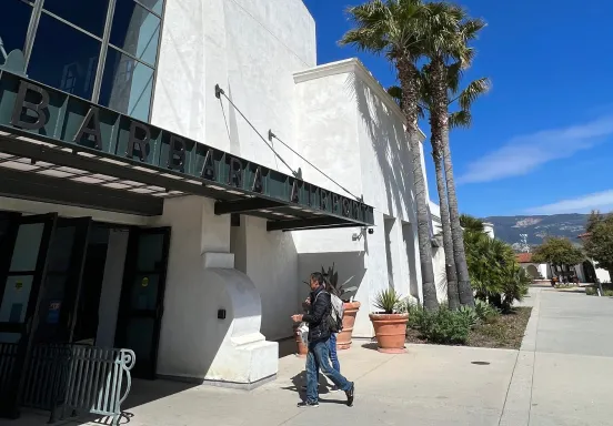 Two people walking into the main entrance of the Santa Barbara Airport Terminal