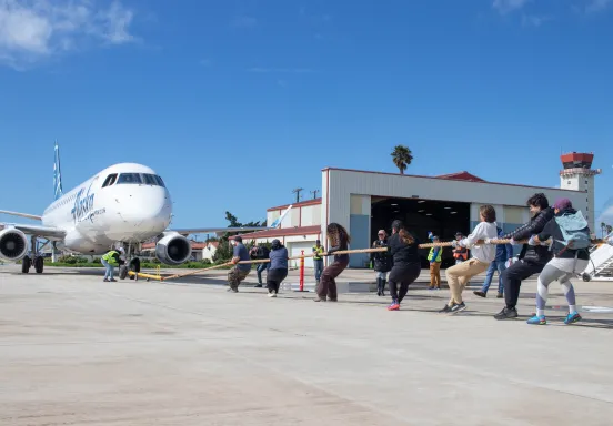 A group of people pull an airplane by a rope.