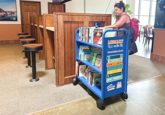 A woman browses the Library on the Fly bookshelf