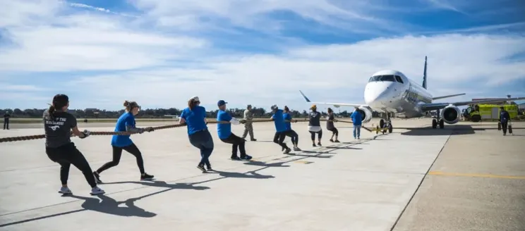 Team of 10 people pulling an airplane with a rope