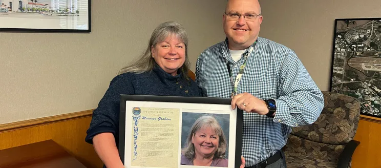 Mo Graham poses with Airport Director Chris Hastert holding a plaque