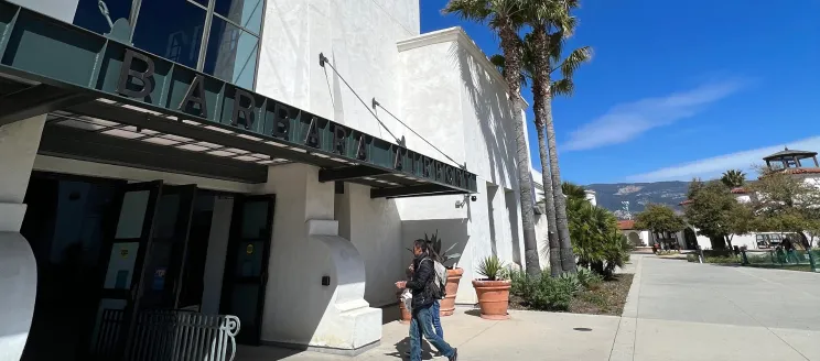Two people walking into the main entrance of the Santa Barbara Airport Terminal