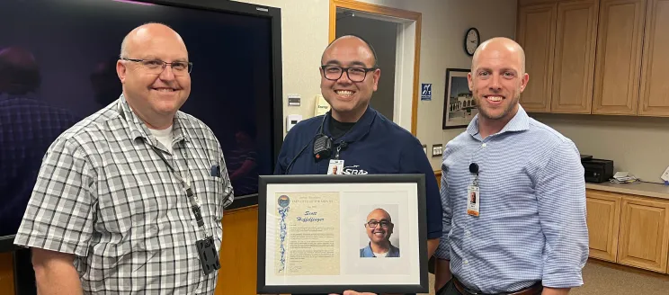 Scott poses with airport staff holding his EOM plaque 