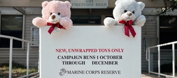 A Toys for Tots box sits in front of the Airport administration office with two teddy bears sitting on top