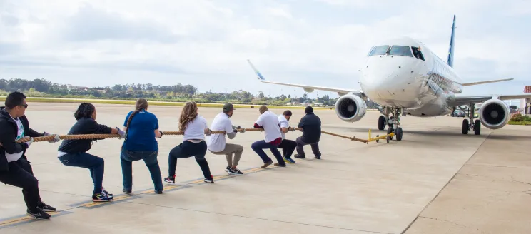 A group of people pull a rope attached to an Alaska Airlines plane at the Santa Barbara Airport.