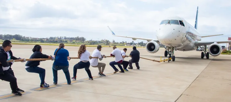 A group of people pull a rope attached to an Alaska Airlines plane at the Santa Barbara Airport.