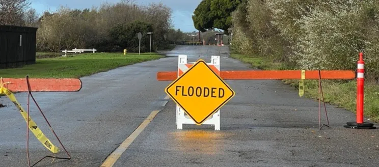 Road with a barricades and a sign that says "flooded"